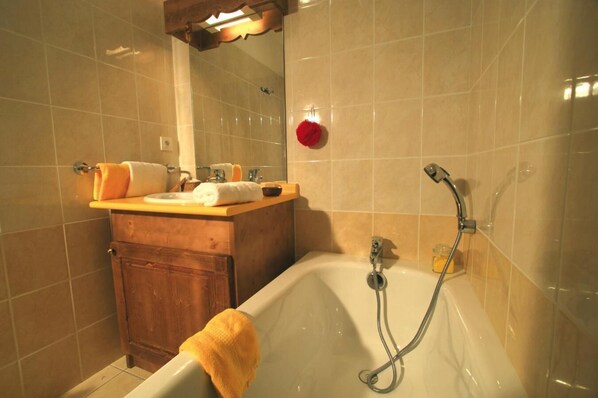 A bathroom with a bathtub, a wooden cabinet, and a mirror.