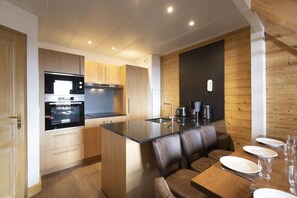 A modern kitchen with a central island, wooden cabinets, and a dining area with a table and chairs.