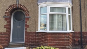 A house with a grey door, a bay window with white trim, and a brick facade. - Shaw Properties Teal Road (Darlington)