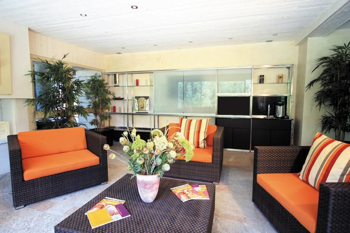 A modern living room with wicker sofas, a coffee table, and a bookshelf.