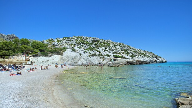 A beach with clear water, rocky terrain, and people sunbathing. - VILLA MADRAVE - FAMILIES AND FRIENDS (Pollensa)
