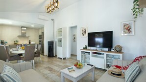 A living room with a sofa, coffee table, TV, and dining area with chairs and a table. - VILLA MADRAVE - FAMILIES AND FRIENDS (Pollensa)