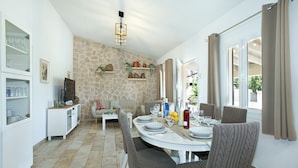 A dining area with a stone wall, a white table set for four, and a view through a glass door. - VILLA MADRAVE - FAMILIES AND FRIENDS (Pollensa)