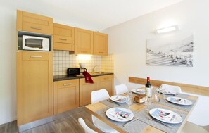 Una cocina moderna con armarios de madera, un microondas y un comedor con una mesa dispuesta para dos.