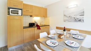 Une cuisine moderne avec des meubles en bois, un four à micro-ondes et un coin repas avec une table dressée pour deux personnes.