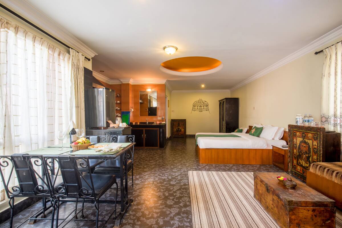 Une chambre d’hôtel comprenant un coin repas, une kitchenette et un lit avec une tête de lit en bois.