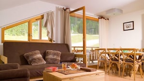 A cozy living room with a sofa, a wooden coffee table, and a dining area with wooden chairs. - Wifi, ski-in/ski-out & foot of the slopes, swimming pool, balcony, 40-50m², Les Orres (Les Orres)