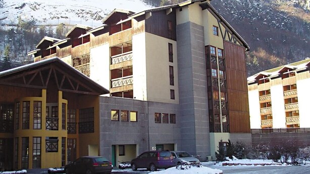 Un hotel de varios pisos con montañas nevadas al fondo, que cuenta con un atrio central y balcones.