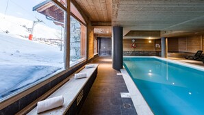 A pool area with a view of a snowy landscape, stone walls, and wooden benches. - 100m from ski slopes, swimming pool, sauna, hammam, balcony, tv, ski locker, 32m², La Toussuire (Fontcouverte-la-Toussuire)