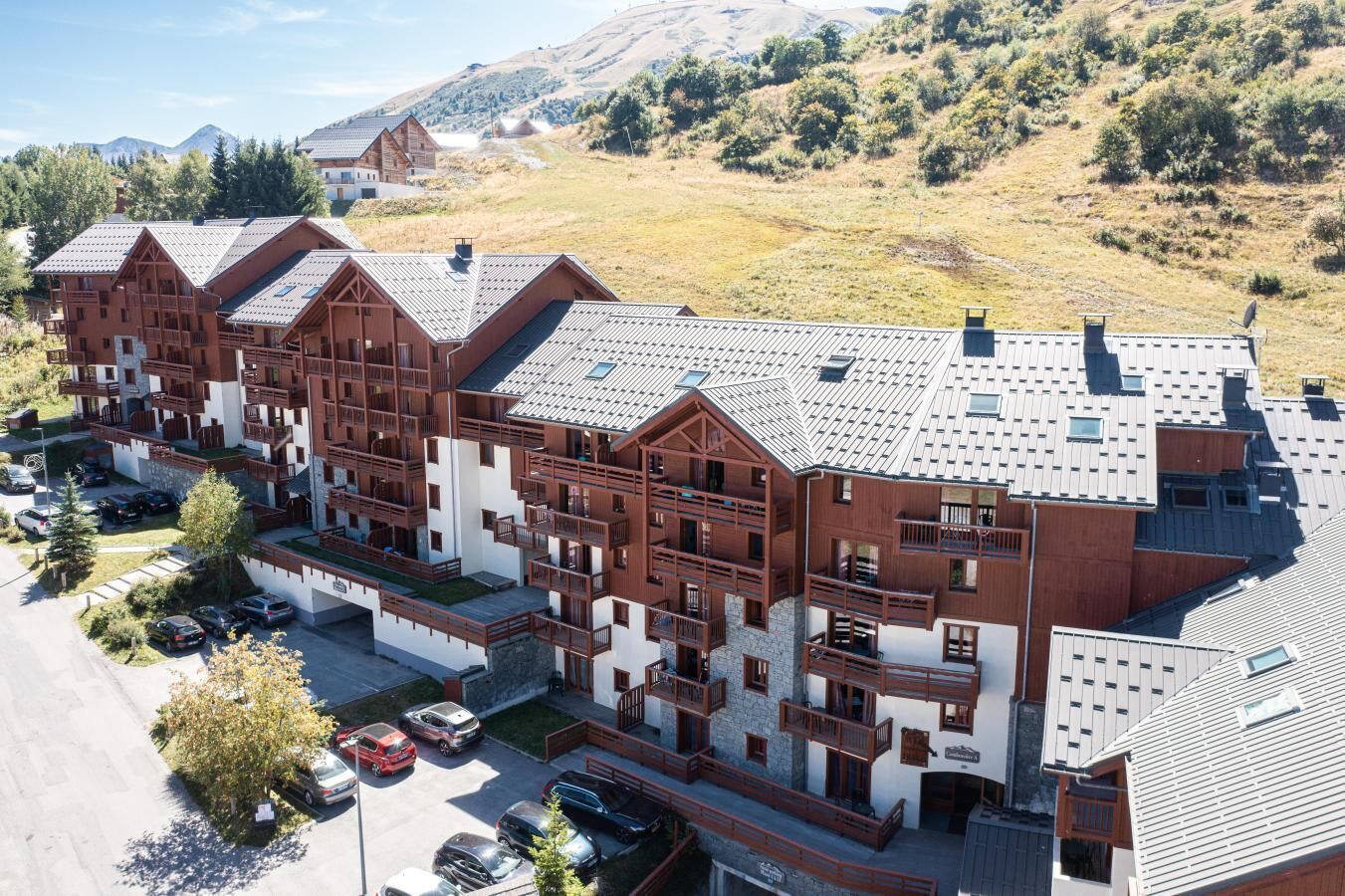 A multi-story hotel with a modern architectural design, featuring balconies and a parking area.