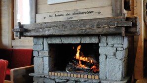 A rustic interior with a stone fireplace, wooden furniture, and a wall-mounted painting of bears. - 100m from ski slopes, swimming pool, sauna, hammam, balcony, tv, ski locker, 32m², La Toussuire (Fontcouverte-la-Toussuire)