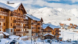 A snow-covered mountain resort with wooden buildings, ski slopes, and a clear sky. - 100m from ski slopes, swimming pool, sauna, hammam, balcony, tv, ski locker, 32m², La Toussuire (Fontcouverte-la-Toussuire)