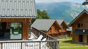 Un chalet en bois doté d’un balcon donnant sur un paysage montagneux.