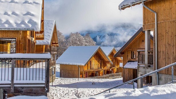 A wooden chalet-style building with a snow-covered roof, a balcony, and a view of mountains in the background. - Wifi, Ground floor, swimming pool, sauna, terrace, balcony, parking, ski locker, 35-42m², La Féclaz (La Féclaz)