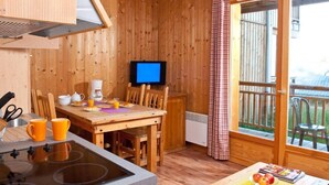 A wooden cabin with a kitchen area, dining table, and a television. - Wifi, Ground floor, swimming pool, sauna, terrace, balcony, parking, ski locker, 35-42m², La Féclaz (La Féclaz)
