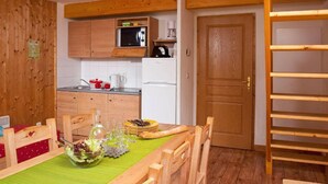 A compact kitchen with wooden cabinets, a microwave, a coffee maker, and a refrigerator. - Wifi, 300m from ski slopes, swimming pool, sauna, terrace, balcony, parking, ski locker, 56m² (La Féclaz)