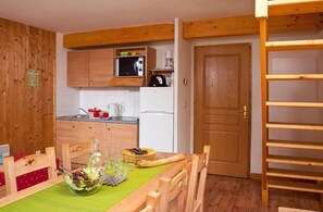 Une cuisine compacte dotée d’armoires en bois, d’un four à micro-ondes, d’une machine à café et d’un réfrigérateur.