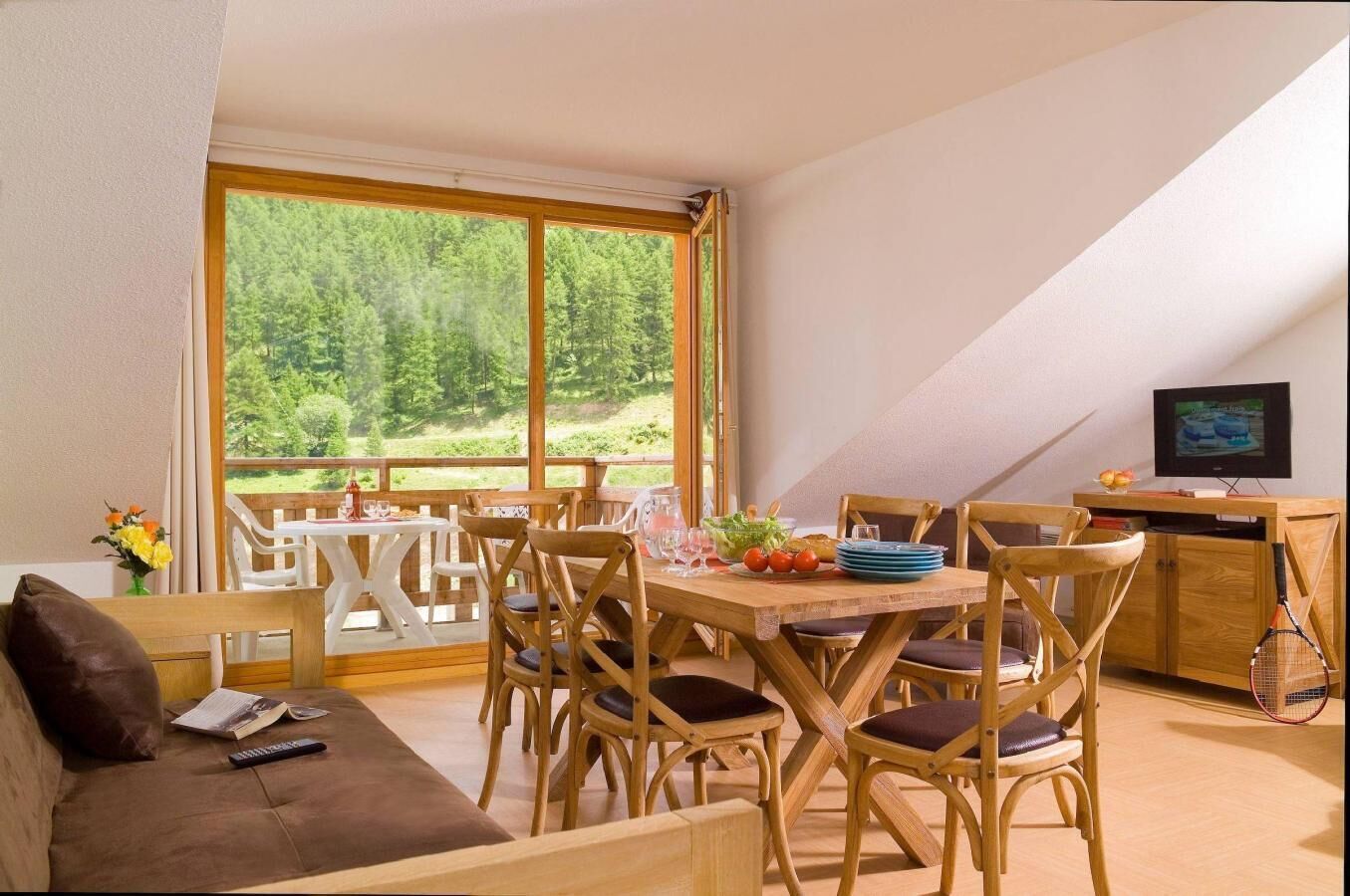 Una habitación acogedora con una mesa de comedor de madera, sillas, un sofá y un televisor.