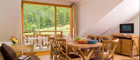 Una habitación acogedora con una mesa de comedor de madera, sillas, un sofá y un televisor.