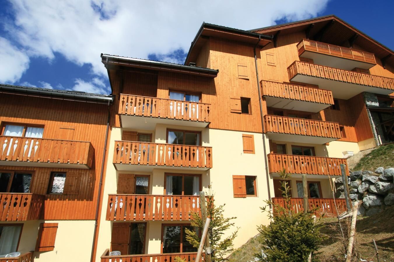 A multi-story building with wooden balconies and a sloped roof, likely a hotel or resort.