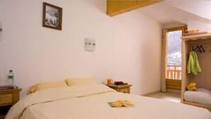 A bedroom with a bed, a bedside table, a nightstand, a window, and a door leading to another room. - 50m from shops, swimming pool, balcony, 36-37m², Les Orres (Les Orres)