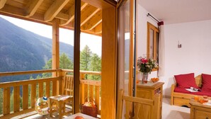 A wooden balcony with a table, chairs, and a view of mountains. - 50m from shops, swimming pool, balcony, 36-37m², Les Orres (Les Orres)