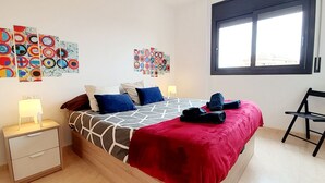 Ein Schlafzimmer mit einem Bett, Nachttischen, einem Sessel und Kunstwerken an den Wänden.
