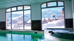 A swimming pool with a view of snow-covered mountains and buildings.