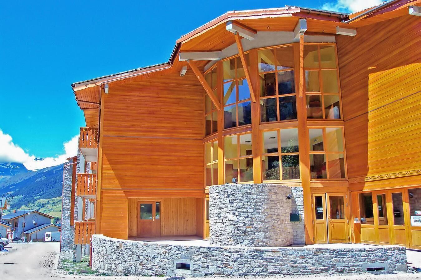 A wooden building with large windows and a stone base.