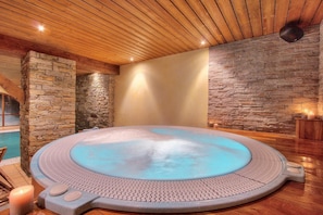 Ein Whirlpool mit Steinwand, Holzboden und einer Steinsäule.