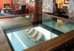 A pool area with lounge chairs, a stone wall, and a wooden deck. - 300m from ski slopes, swimming pool, sauna, hammam, terrace, balcony, tv, ski locker, 37m² (La Plagne)