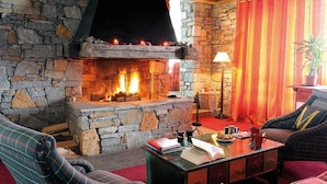 A cozy living room with a stone fireplace, plaid furniture, and a red curtain. - 300m from ski slopes, swimming pool, sauna, hammam, terrace, balcony, tv, ski locker, 37m² (La Plagne)