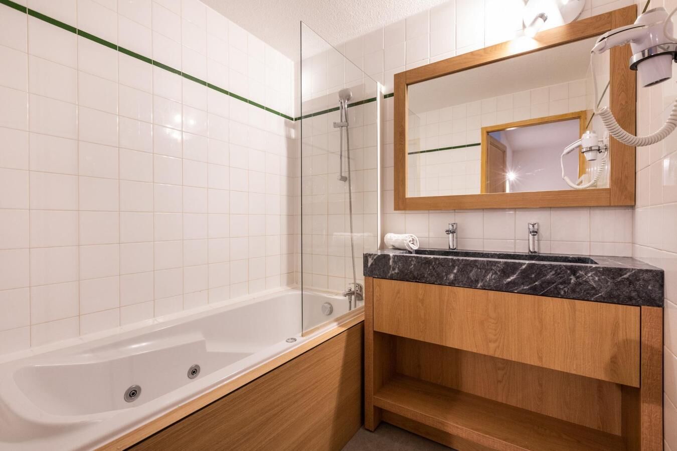 A modern bathroom with a bathtub, a shower, a vanity with a mirror, and a hairdryer.