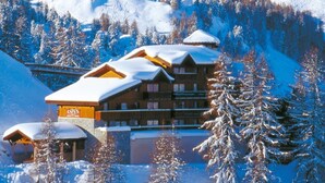 En hytte med flere etager, snedækkede tage og et skilt med 'ASPEN'.