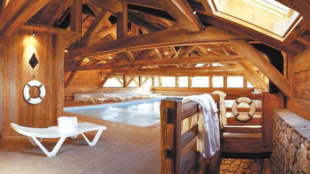 An indoor swimming pool with wooden beams and stone walls, surrounded by lounge chairs and a bench. - Fitness, swimming pool, balcony, tv, ski locker, 35m², Les Saisies (Les Saisies)