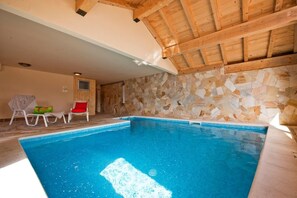 En swimmingpool med en vägg av sten och ett tak av trä.