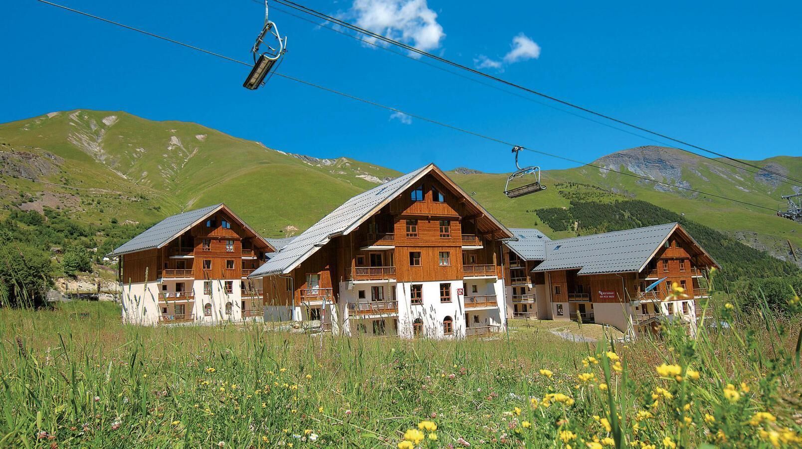 Een chalet met meerdere balkons, een skilift op de achtergrond en een bergachtig landschap.