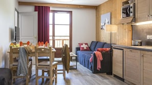 Um quarto acolhedor com uma mesa de jantar de madeira, um sofá e uma cozinha equipada com micro-ondas e armários.