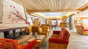 A spacious lounge area with wooden furniture, a fireplace, and stone pillars. - 200m from ski slopes, fitness, swimming pool, terrace, balcony, tv, ski locker, 50-55m² (Saint-Chaffrey)