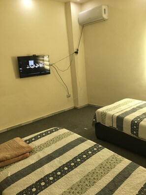 A hotel room with two beds, a flat-screen TV mounted on the wall, and an air conditioning unit. - Serres (Amman)