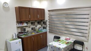 Una cocina compacta con armarios de madera, un refrigerador, un lavamanos y una mesa con mantel floral.