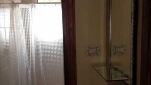Un baño con inodoro, espejo y cortina de ducha.