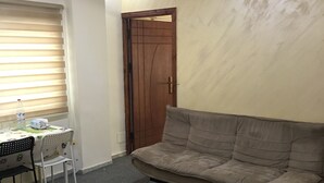 Una habitación pequeña amoblada con sofá, una mesa y sillas, y una puerta.