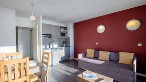 Eine moderne Wohnung mit Küche, Essbereich und Wohnzimmer mit roter Akzentwand.