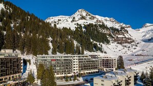 Ein mehrstöckiges Hotel mit einem Skigebiet im Hintergrund.