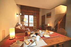 Ein Essbereich mit einem Holztisch, gedeckt für das Frühstück, einer Couch und einer Treppe.