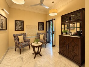 A room with two patterned armchairs, a small round table with a plant, a cabinet with glass doors, and a ceiling fan. - King’s Abode - Luxuria Ranakpur by Moustache (Desuri)