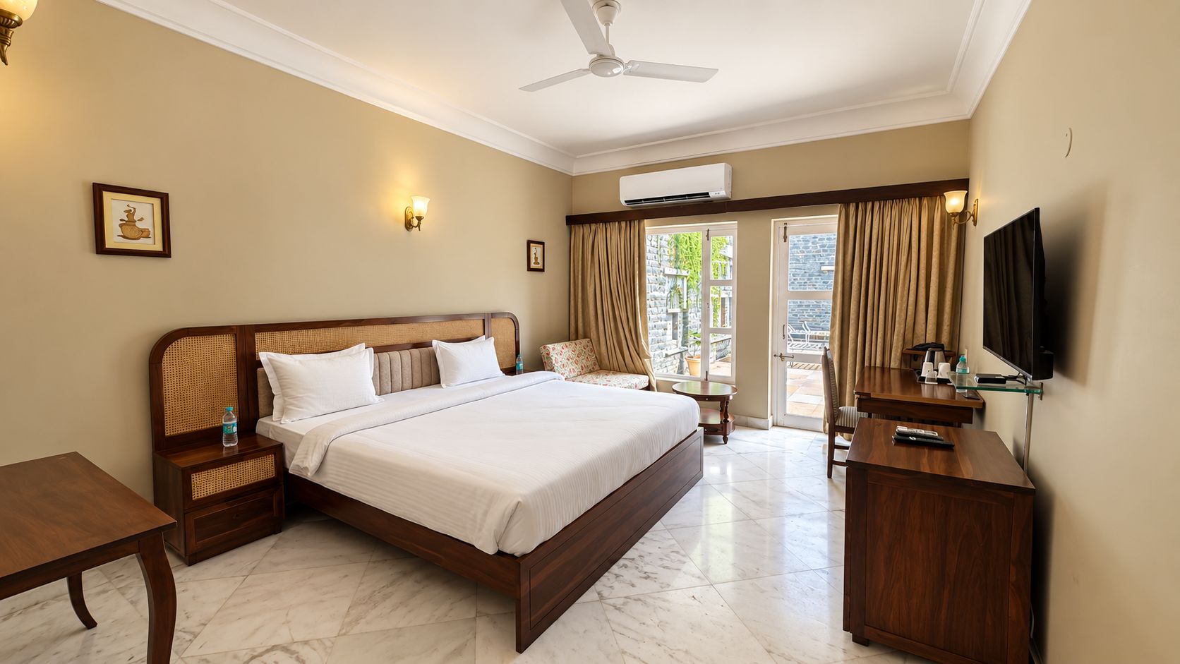 A hotel room with a large bed, a desk, a television, and a ceiling fan.