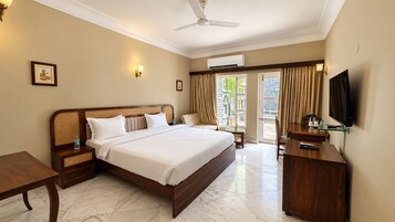 Una habitación de hotel con una cama grande, un escritorio, un televisor y un ventilador de techo.
