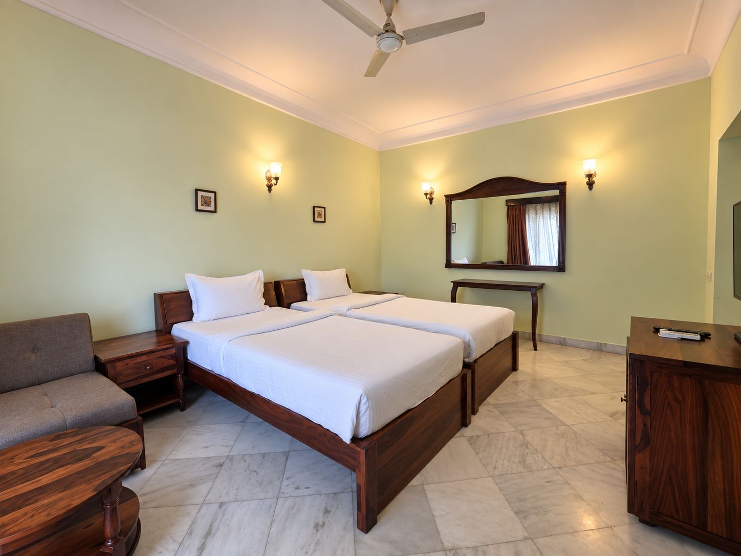 A hotel room with a large bed, a desk, a chair, and a ceiling fan.